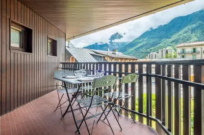 a balcony with a table and chairs with a view at Superbe appartement avec parking gratuit en centre ville et aux pieds des pistes in Chamonix-Mont-Blanc