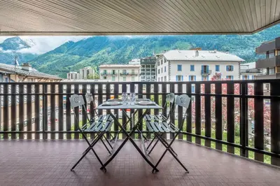 a table and chairs on a balcony with a view at Superbe appartement avec parking gratuit en centre ville et aux pieds des pistes in Chamonix-Mont-Blanc