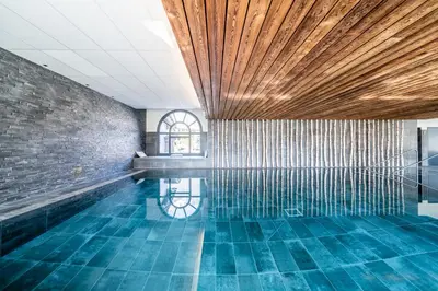 a swimming pool with a brick wall and blue tiles at Apartment Le Gui Chamonix - BY EMERALD STAY in Chamonix-Mont-Blanc