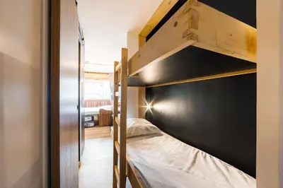 a small bedroom with a bunk bed with a black wall at Studio l'Orée - City centre - Megève in Megève