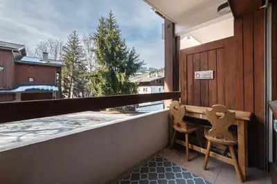 a balcony with two chairs and a table and a window at Studio l'Orée - City centre - Megève in Megève