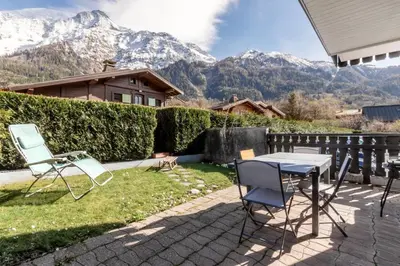 a table and chairs on a patio with mountains in the background at Lilas - Awesome view of the Mont-Blanc Range in Les Houches