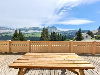 a wooden table on a deck with a view of mountains at Chalet confortable à Flaine avec poêle et WIFI - FR-1-425-198 in Arâches-la-Frasse