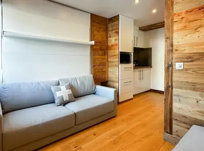 a living room with a couch and a kitchen at Pti bout villlage Megeve in Megève