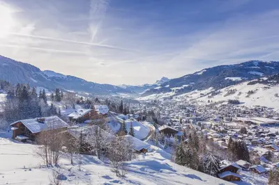 a village covered in snow with mountains in the background at Pti bout villlage Megeve in Megève