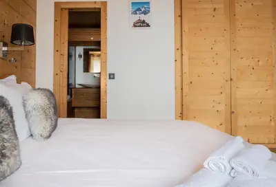 a bedroom with a white bed and wooden walls at Luxury Wood Megeve village in Megève