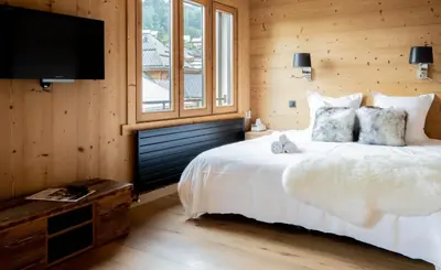 a bedroom with a white bed and a television at Luxury Wood Megeve village in Megève