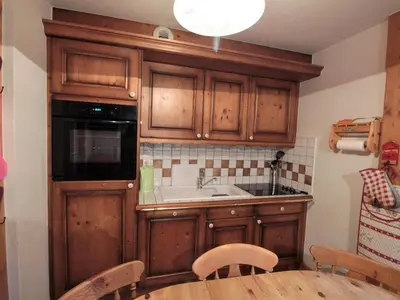 a kitchen with wooden cabinets and a sink and a table at Appartement 3 pièces cabine, 6 pers, face au spa et au ski bus, proche pistes et commodités - FR-1-572-45 in Arâches-la-Frasse
