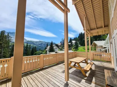 a wooden deck with a wooden picnic table on it at Résidence Hameau - Chalet confortable · Poêle à bois · Terrasse · Garage · WIFI gratuit MAE-8714 in Magland