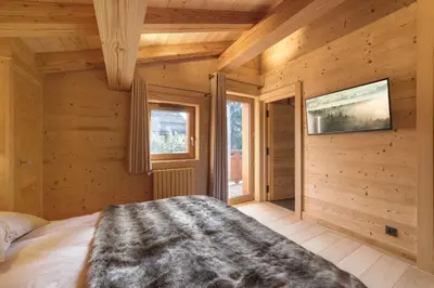 a bedroom with wooden walls and a bed in a room at Pas de l’Ourson - Megève - Chalet with Sauna in Megève