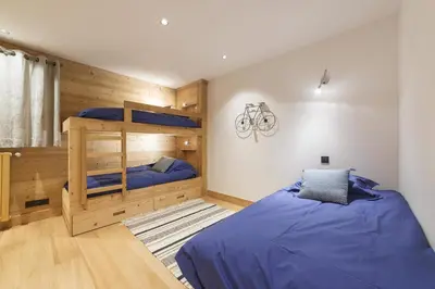 a bedroom with two bunk beds with blue sheets at Pas de l’Ourson - Megève - Chalet with Sauna in Megève