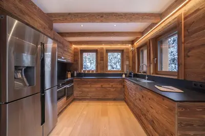 a kitchen with a stainless steel refrigerator and wooden walls at Pas de l’Ourson - Megève - Chalet with Sauna in Megève