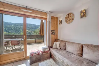a living room with a couch and a large window at Duplex familial - Piscine intérieure in Saint-Gervais-les-Bains