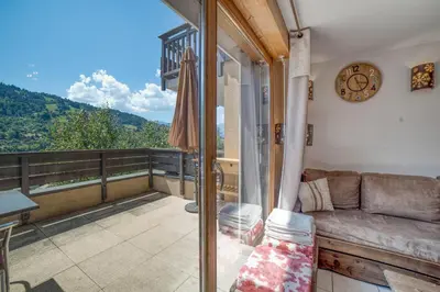 a living room with a couch and a clock on a balcony at Duplex familial - Piscine intérieure in Saint-Gervais-les-Bains