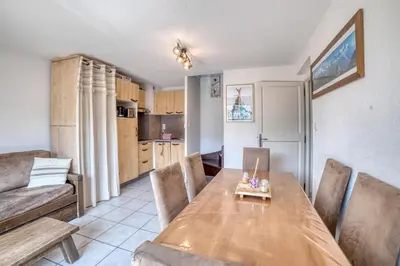 a dining room and kitchen with a wooden table and chairs at Duplex familial - Piscine intérieure in Saint-Gervais-les-Bains