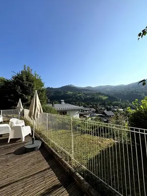 a deck with white furniture and a view of a city at Duplex familial - Piscine intérieure in Saint-Gervais-les-Bains