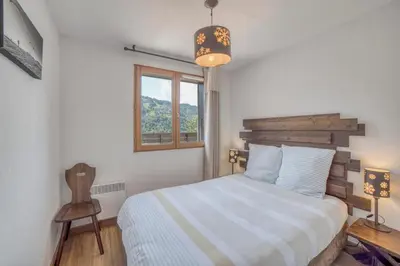 a bedroom with a bed and a window and a chair at Duplex familial - Piscine intérieure in Saint-Gervais-les-Bains