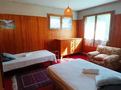 a hotel room with two beds and a chair at La Maison des Praz in Saint-Gervais-les-Bains