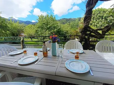 a white table with plates and a vase of flowers at La Maison des Praz in Saint-Gervais-les-Bains