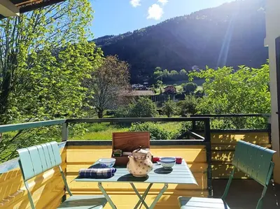 a patio with a table and chairs on a balcony at La Maison des Praz in Saint-Gervais-les-Bains