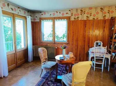 a living room with a table and chairs and windows at La Maison des Praz in Saint-Gervais-les-Bains