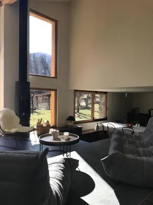 a living room with couches and a table and windows at LE REFUGE DE LUCE in Saint-Gervais-les-Bains