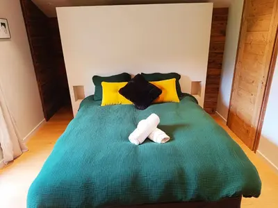 a bedroom with a green bed with yellow pillows at LE REFUGE DE LUCE in Saint-Gervais-les-Bains