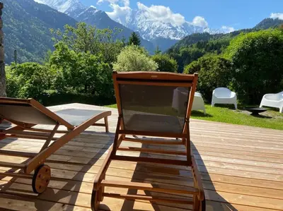 a rocking chair on a deck with mountains in the background at LE REFUGE DE LUCE in Saint-Gervais-les-Bains
