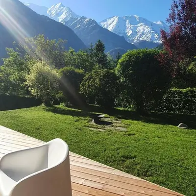 a white bench sitting on a deck with mountains in the background at LE REFUGE DE LUCE in Saint-Gervais-les-Bains