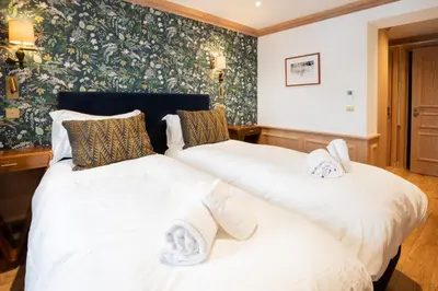 two twin beds in a room with floral wallpaper at Chalet Albert 1 er Megeve village in Megève