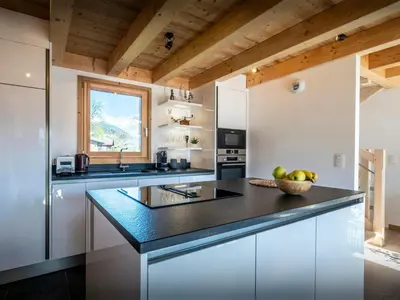 a kitchen with white cabinets and a black counter top at Chalet Alpayak - OVO Network in Combloux