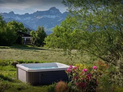 a hot tub in a field with mountains in the background at Chalet Alpayak - OVO Network in Combloux
