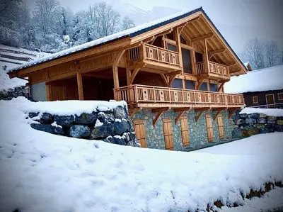a log cabin with a deck in the snow at Chalet****Luxe Sauna & SPA Le Champenois in Samoëns