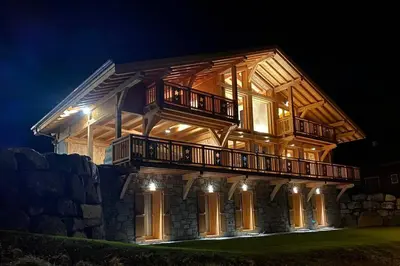 a large wooden house with a deck at night at Chalet****Luxe Sauna & SPA Le Champenois in Samoëns