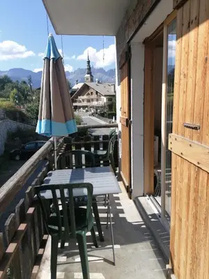 a table and chairs with an umbrella on a balcony at chalet Mont-Blanc in Combloux