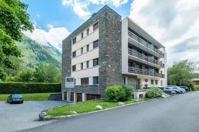 a building with cars parked in a parking lot at Appartement Cosy, Chamonix Centre in Chamonix-Mont-Blanc