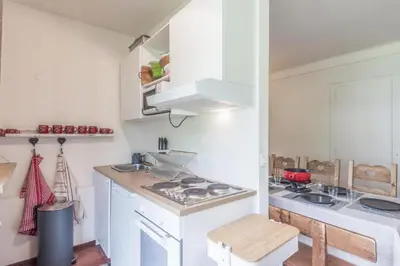 a kitchen with white cabinets and a stove top oven at Appartement Cosy, Chamonix Centre in Chamonix-Mont-Blanc