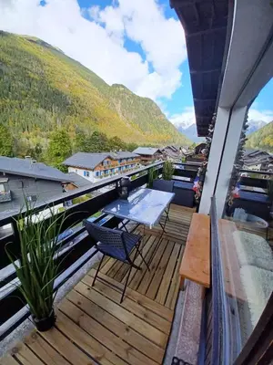 a balcony with a table and chairs and a mountain at Refuge des Alpages - Duplex - Vue Aiguillette des Houches in Les Houches