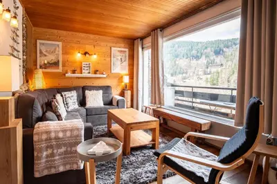 a living room with a couch and a large window at Refuge des Alpages - Duplex - Vue Aiguillette des Houches in Les Houches