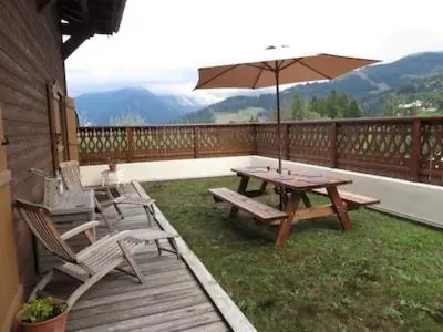a patio with a table and chairs and an umbrella at Vue splendide Mont Blanc in Saint-Gervais-les-Bains