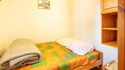 a small bedroom with a bed with a colorful blanket at Les Eterlous- 19- Appart pied des pistes- 6 pers in Morillon