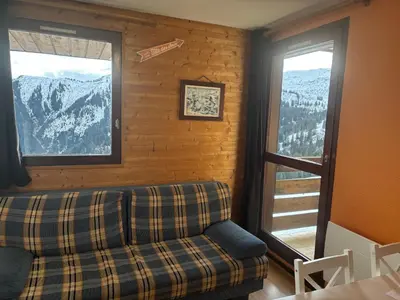 a living room with a couch and two windows at Samoens 1600 les cimes in Samoëns