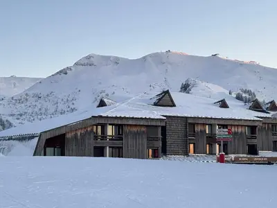 a building covered in snow with a mountain in the background at Samoens 1600 les cimes in Samoëns