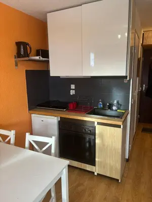 a kitchen with white cabinets and a sink and a table at Samoens 1600 les cimes in Samoëns