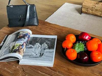 a book next to a bowl of fruit and a bowl of oranges at Stallion d15 MEGEVE in Megève