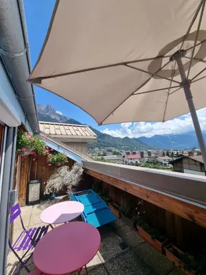 a balcony with two tables and an umbrella at Vue magique in Sallanches