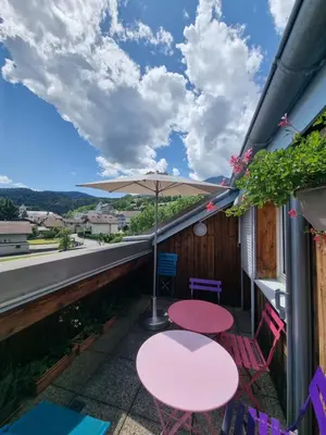 a patio with a table and chairs and an umbrella at Vue magique in Sallanches