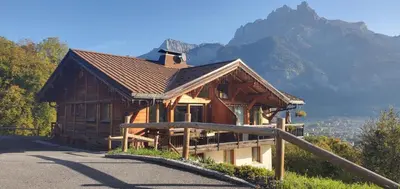 a wooden building with a mountain in the background at SUPERBE DEMI CHALET LUXUEUX 120M² 8 Personnes à SALLANCHES. in Sallanches