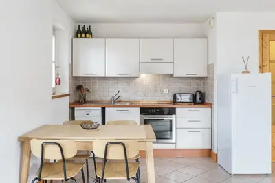 a kitchen with white cabinets and a wooden table at Conseil B - Chic 2BR City Center Apartment - Free Parking & Mountain View - By Cozee Rentals in Saint-Gervais-les-Bains