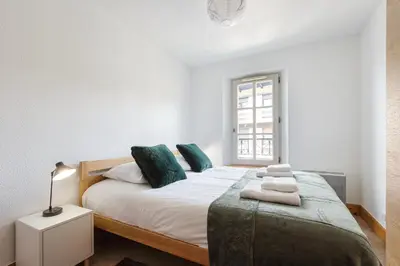 a white bedroom with a large bed with green pillows at Conseil B - Chic 2BR City Center Apartment - Free Parking & Mountain View - By Cozee Rentals in Saint-Gervais-les-Bains